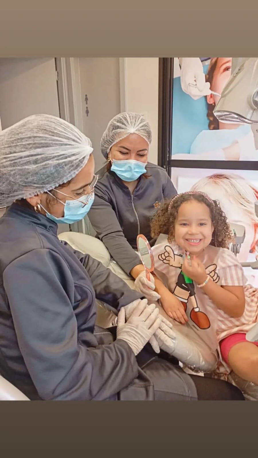 Criança sorrindo com espelho na mão durante consulta na Anavoig